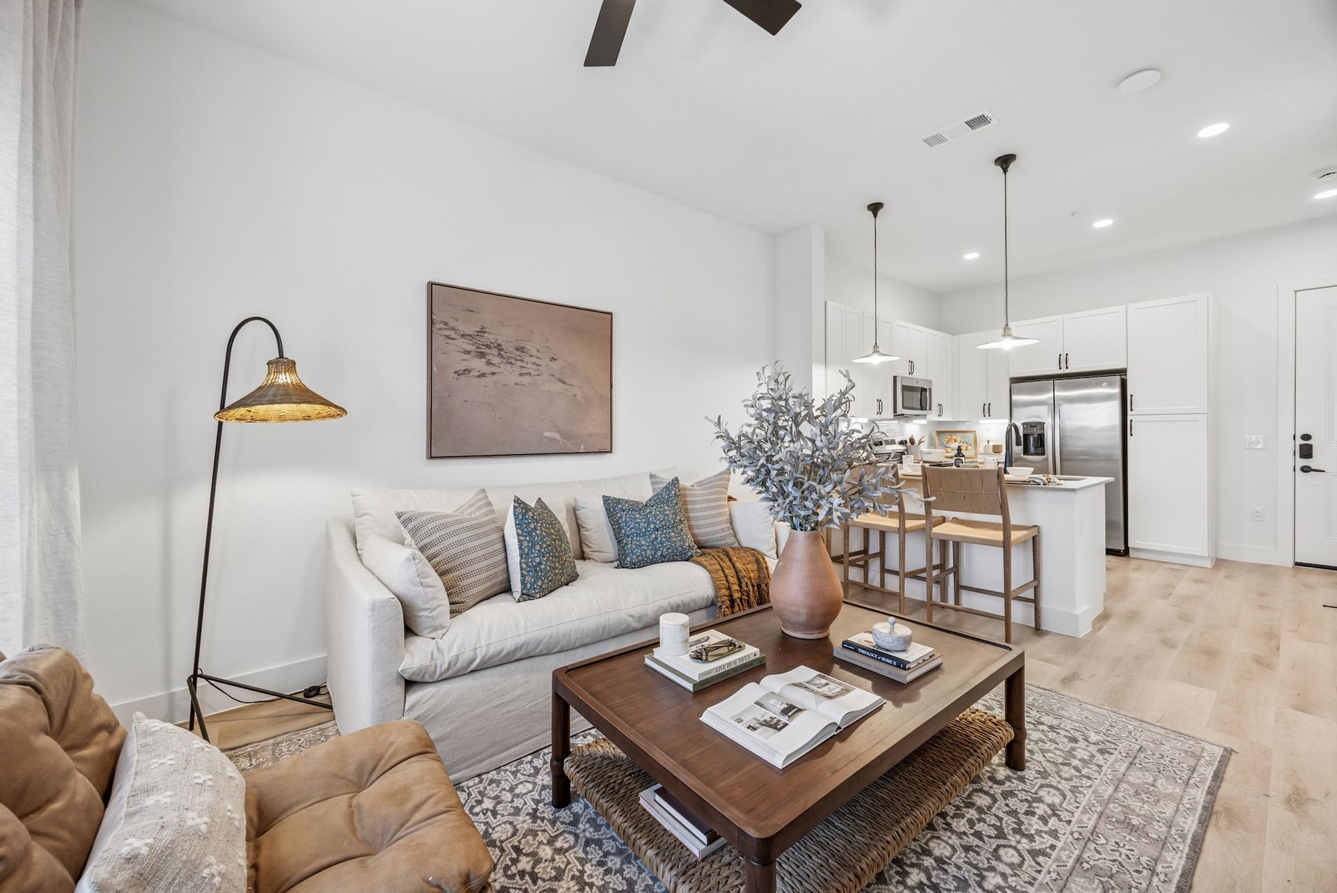 A living room with a couch , chair , coffee table and ceiling fan.