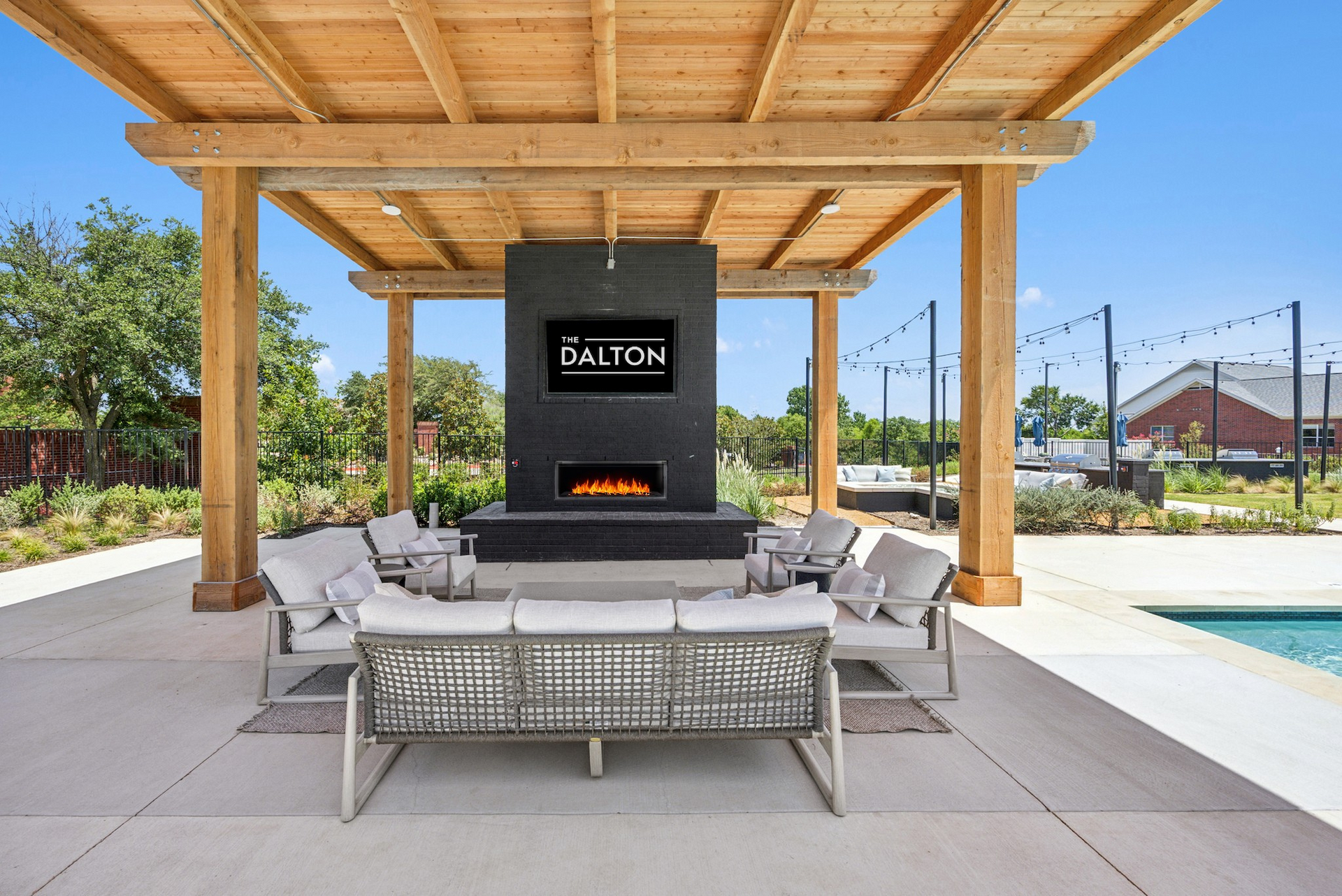 A patio with a fireplace , couch , chairs and a television.