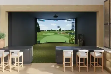 A rendering of a golf simulator with a bar and stools