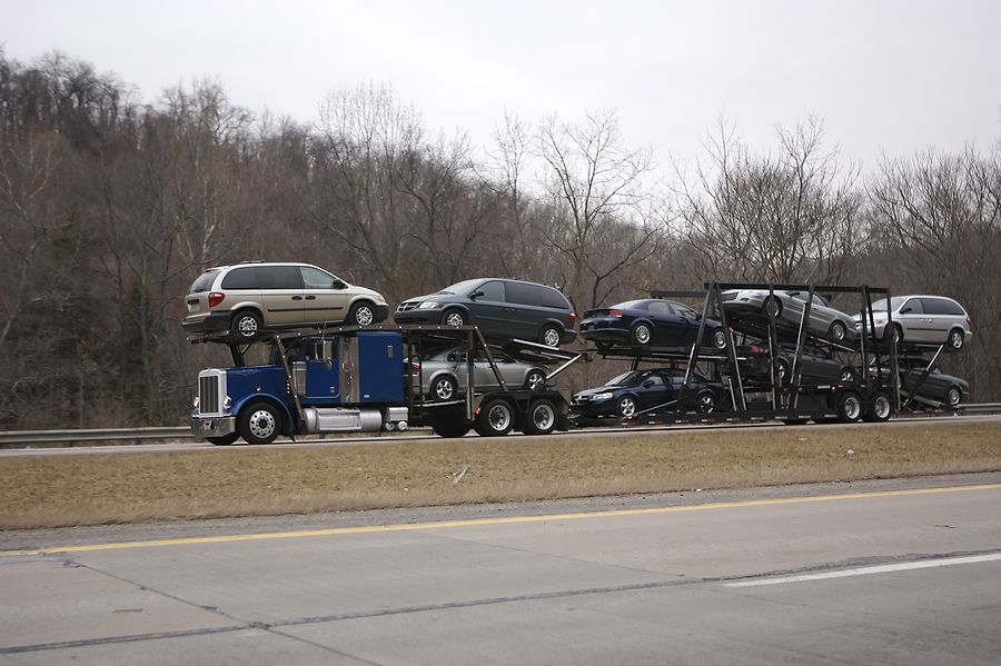 A blue truck carrying a bunch of cars on top of it
