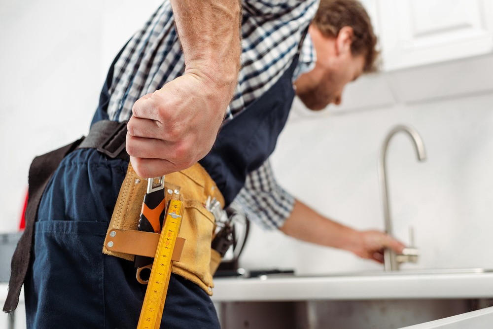 a man is measuring a sink with a tape measure