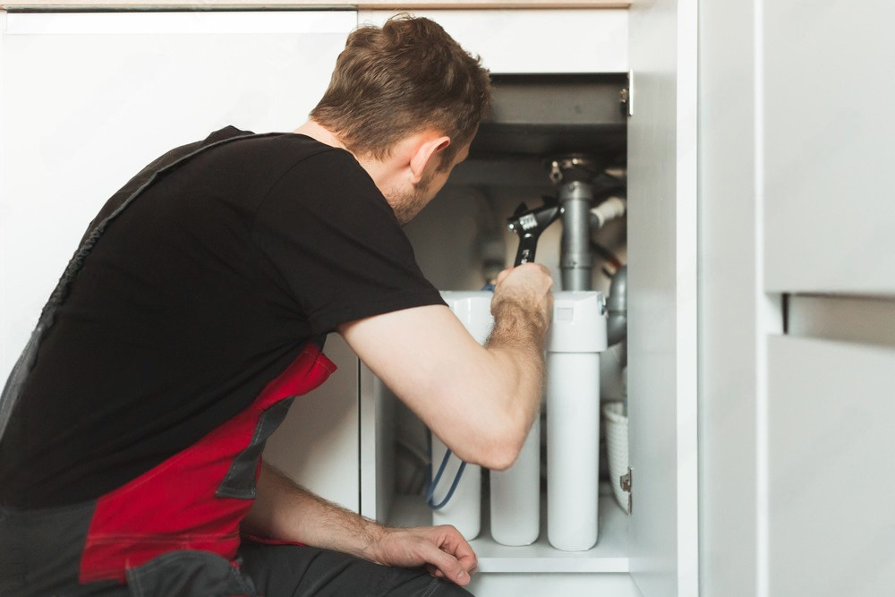 a man is working under a sink with a wrench