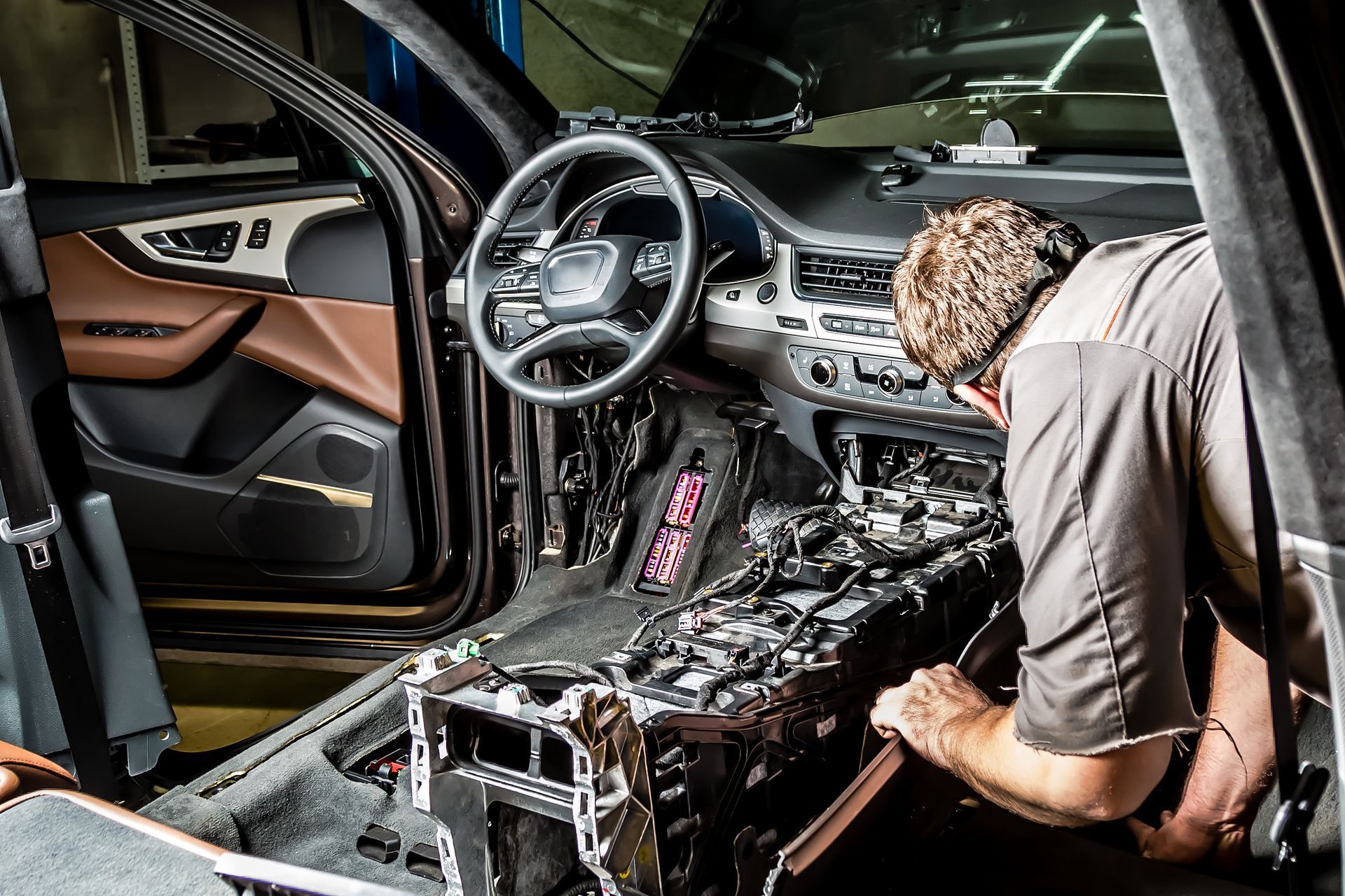 A man is engaged in Audi services, repairing a car in a well-equipped garage with various tools.