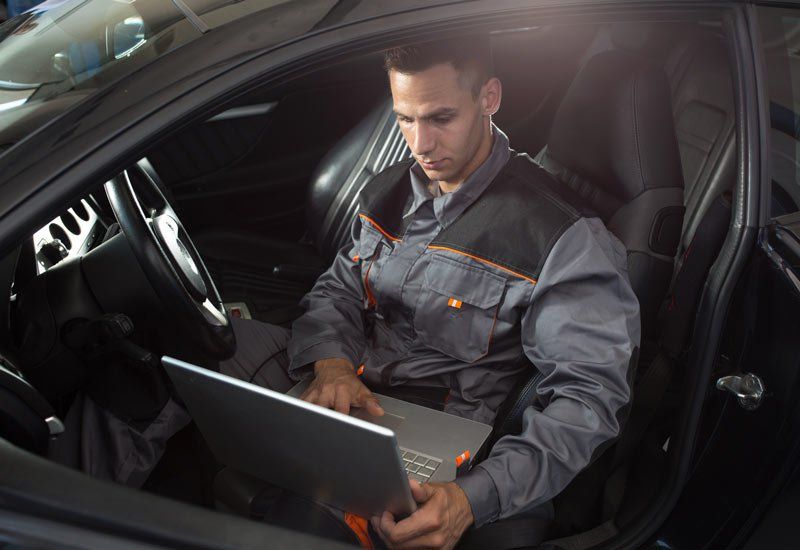 Car Mechanic Using Laptop Inside A Car — St. Louis MO — Legends Detailing Co