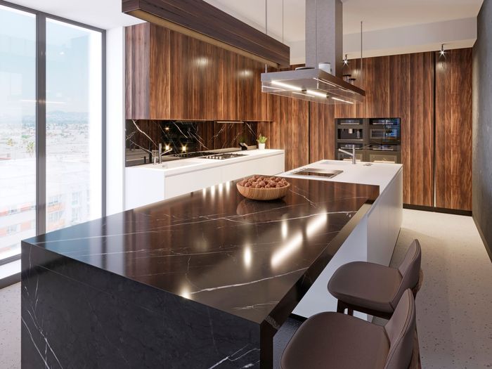 Modern kitchen with dark countertops, wooden cabinetry, and an island with seating.
