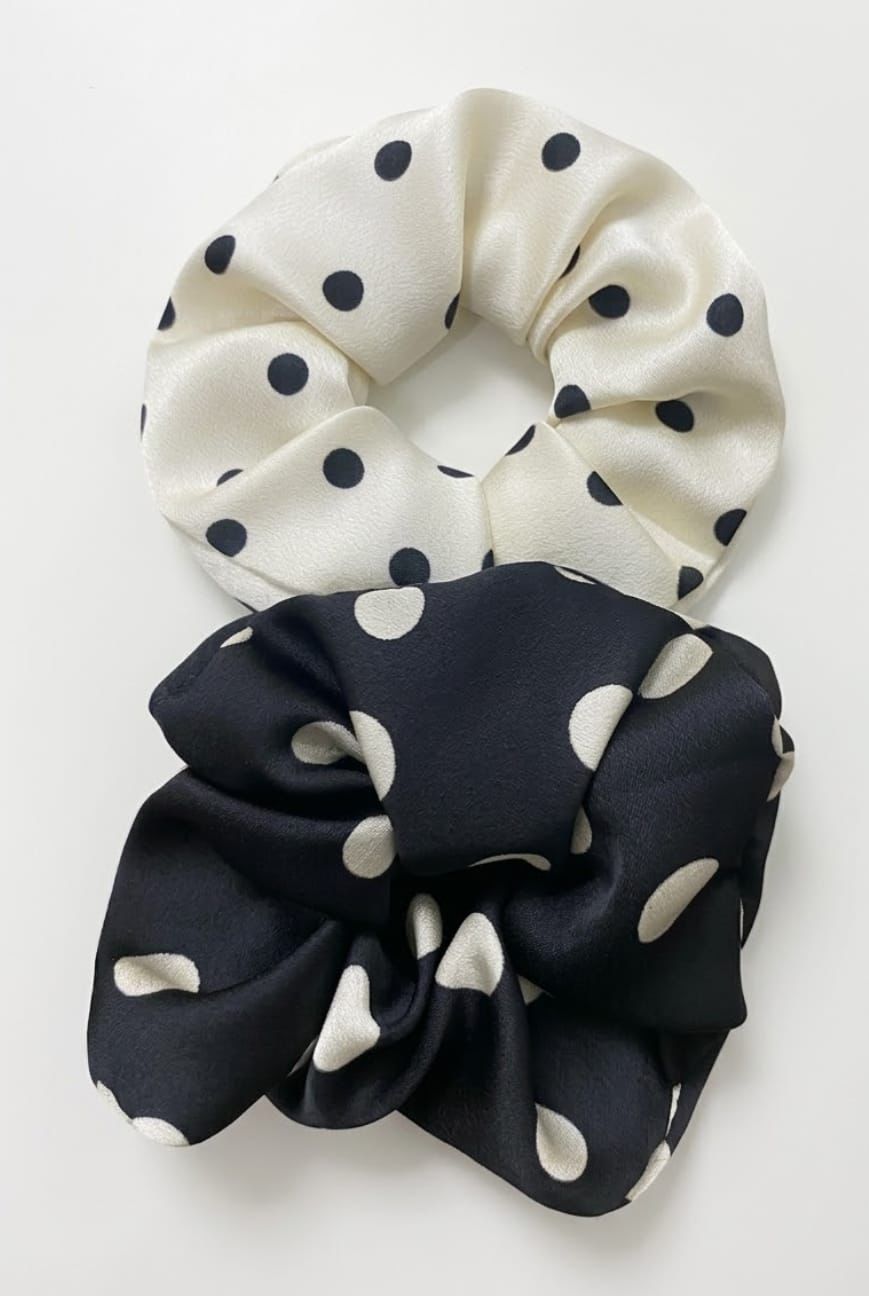 Dos coleteros: uno blanco con lunares negros y otro negro con lunares blancos, sobre un fondo blanco.