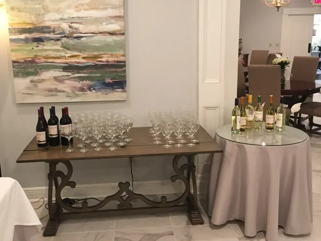 Wine and glasses arranged on a sideboard and cocktail table at a formal indoor event