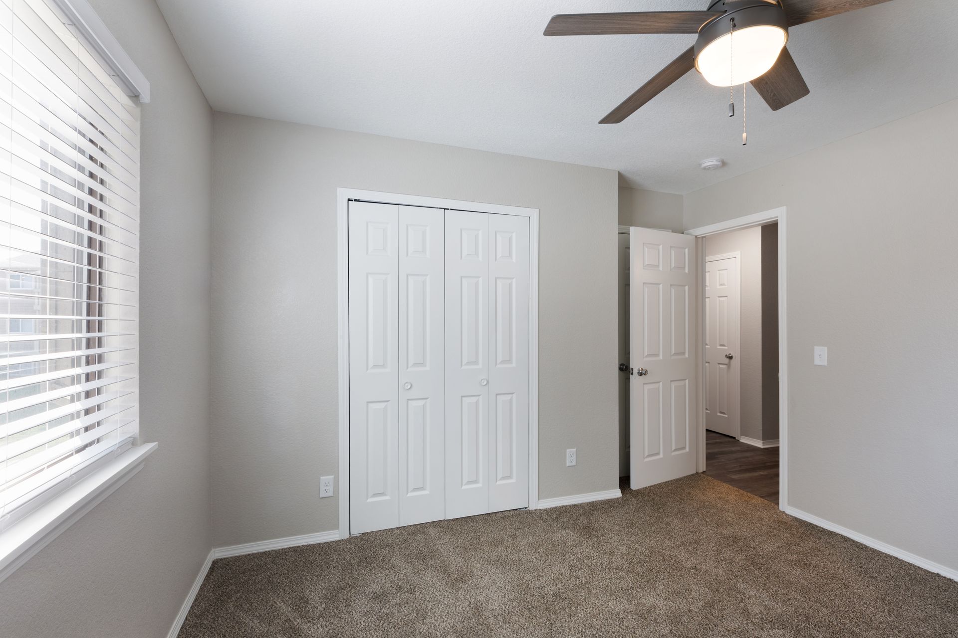 Bedroom with neutral walls, carpet, closet, window with blinds, and ceiling fan.