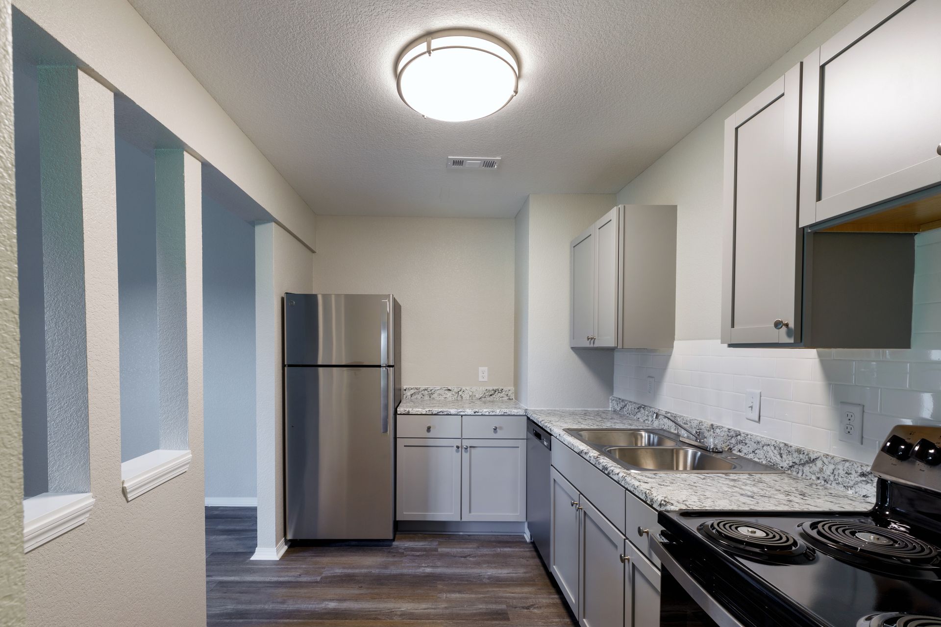 Kitchen with gray cabinets, stainless steel appliances, and granite countertops.
