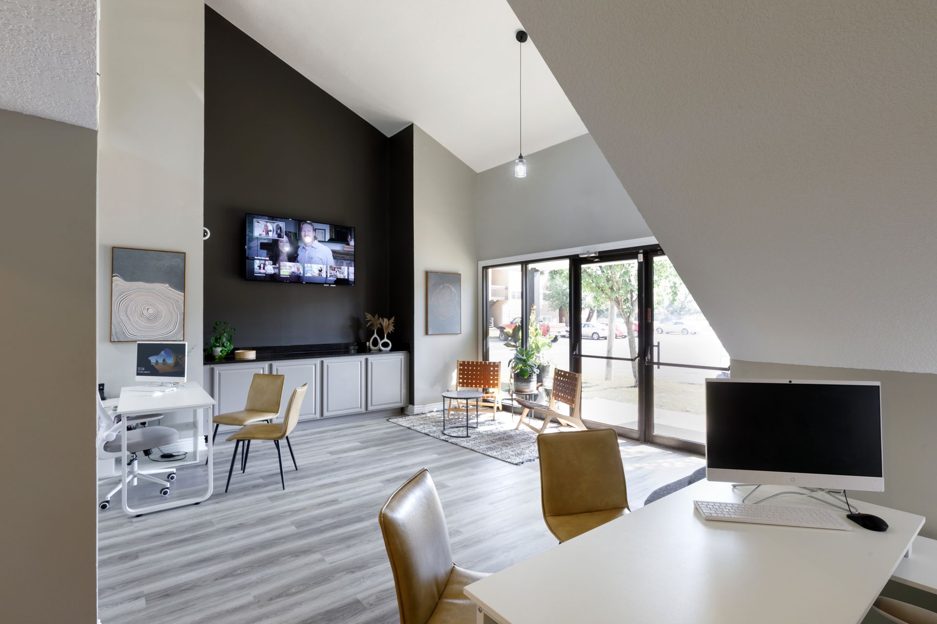 Modern office lobby with desk, chairs, TV, and doors leading outside.