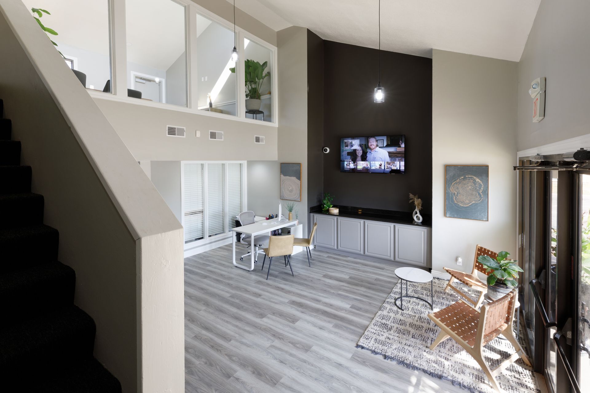 Modern office interior with gray walls, open stairs, seating area, and reception desk.