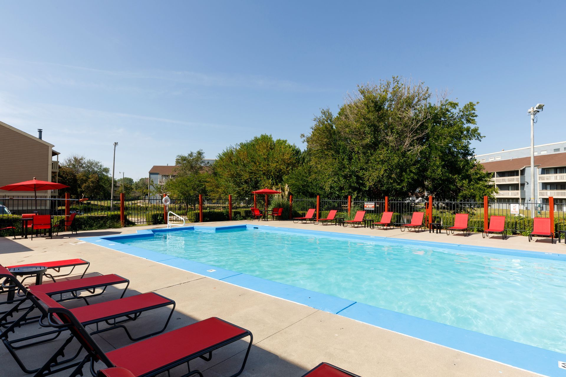 Pool with red lounge chairs and lifeguard station on a sunny day.