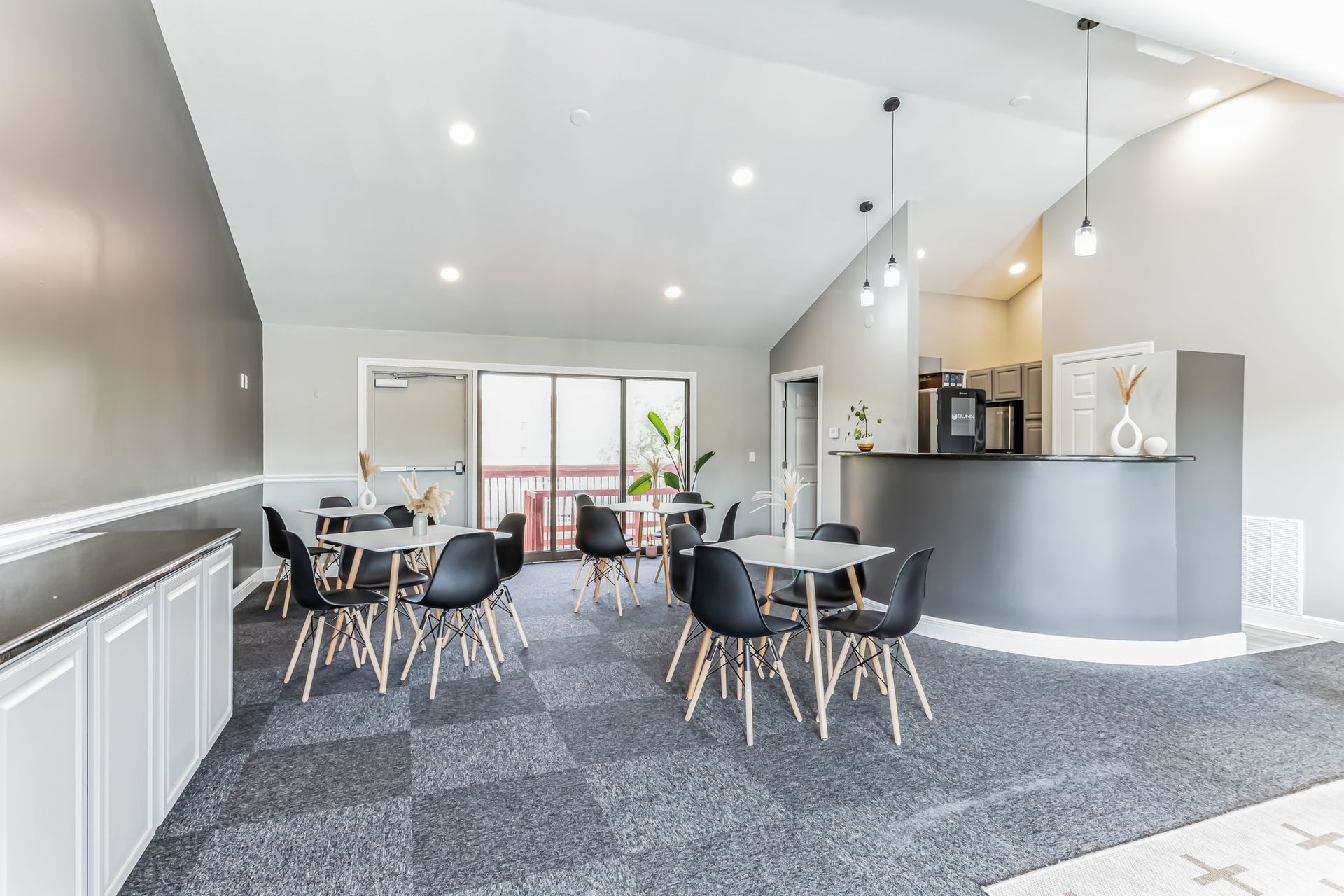 Interior of a lounge with tables, chairs, and a counter area with coffee machines.