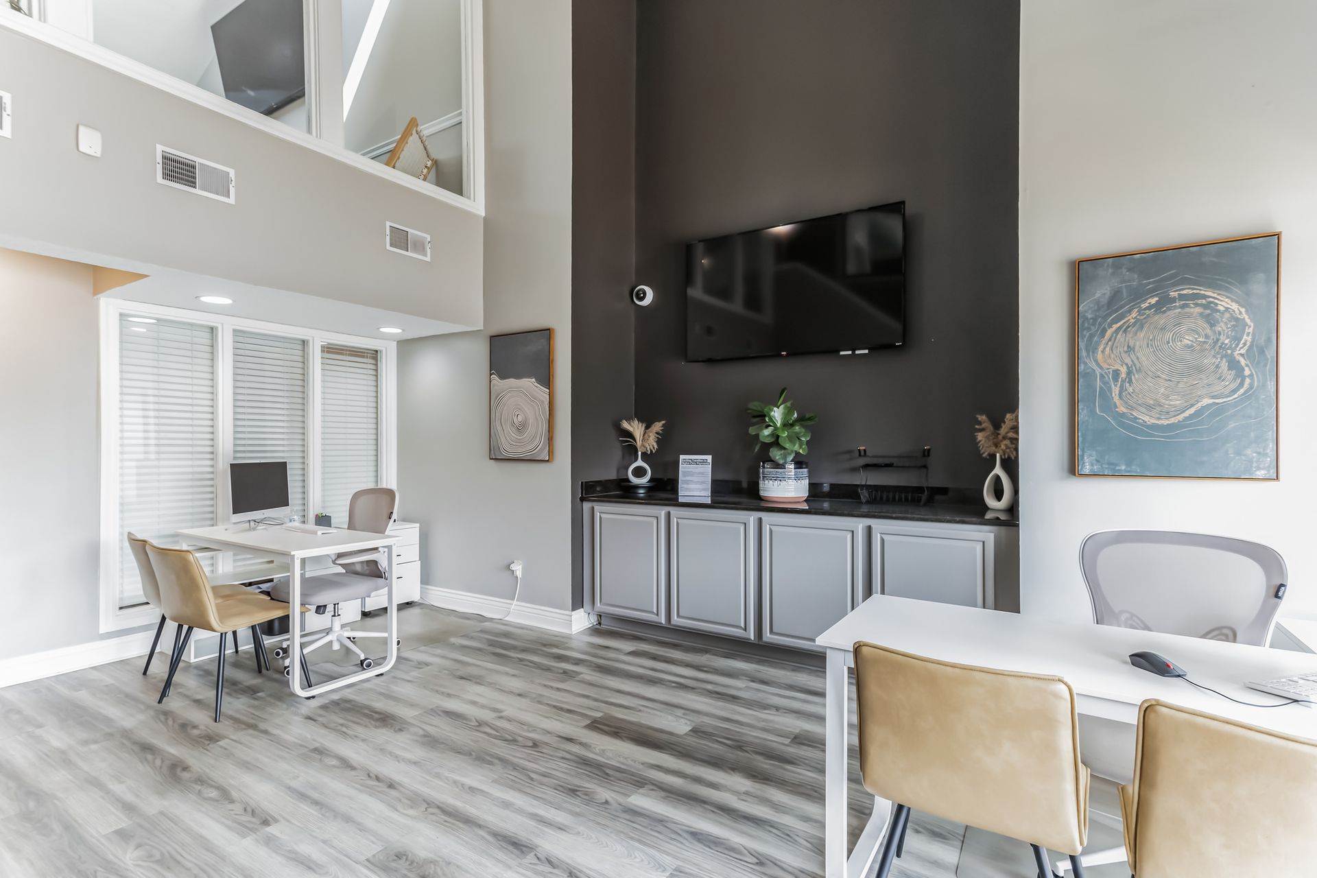 Lobby with desks, chairs, TV, and cabinets. Gray walls, wood floors.