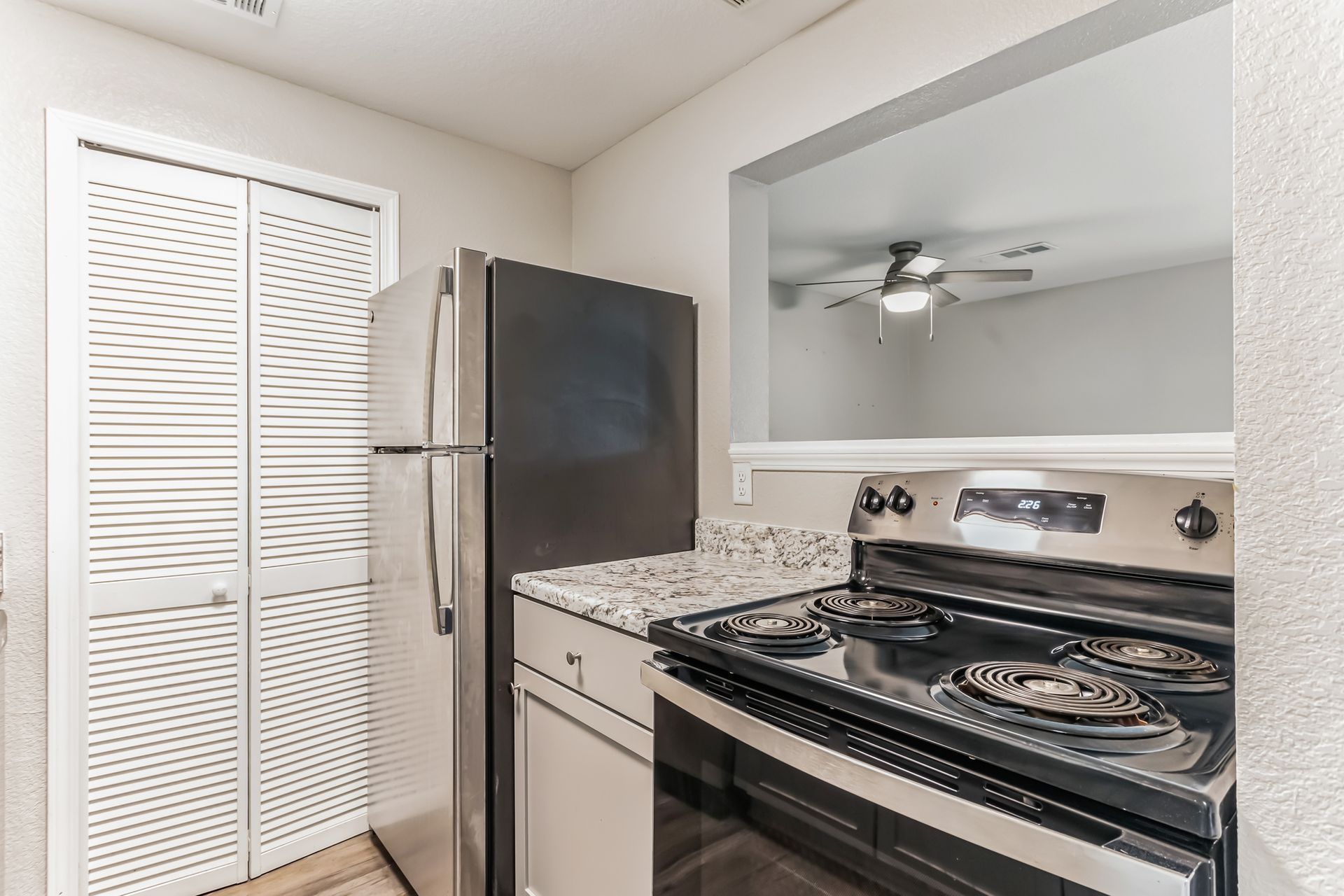 Kitchen with stainless steel appliances, light countertops, and a view of a living area.