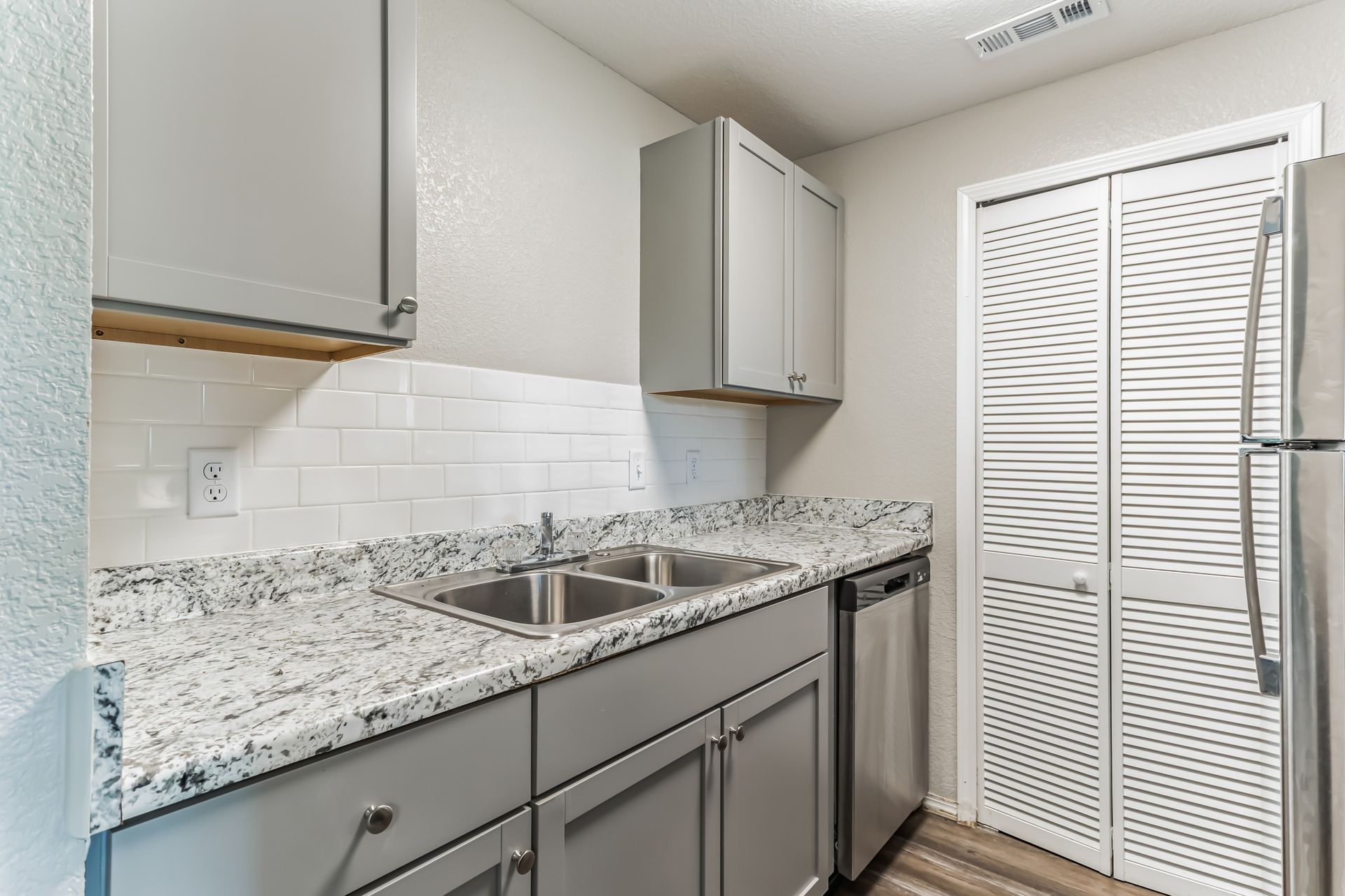 Gray and white kitchen with stainless steel appliances, cabinets, and countertops.