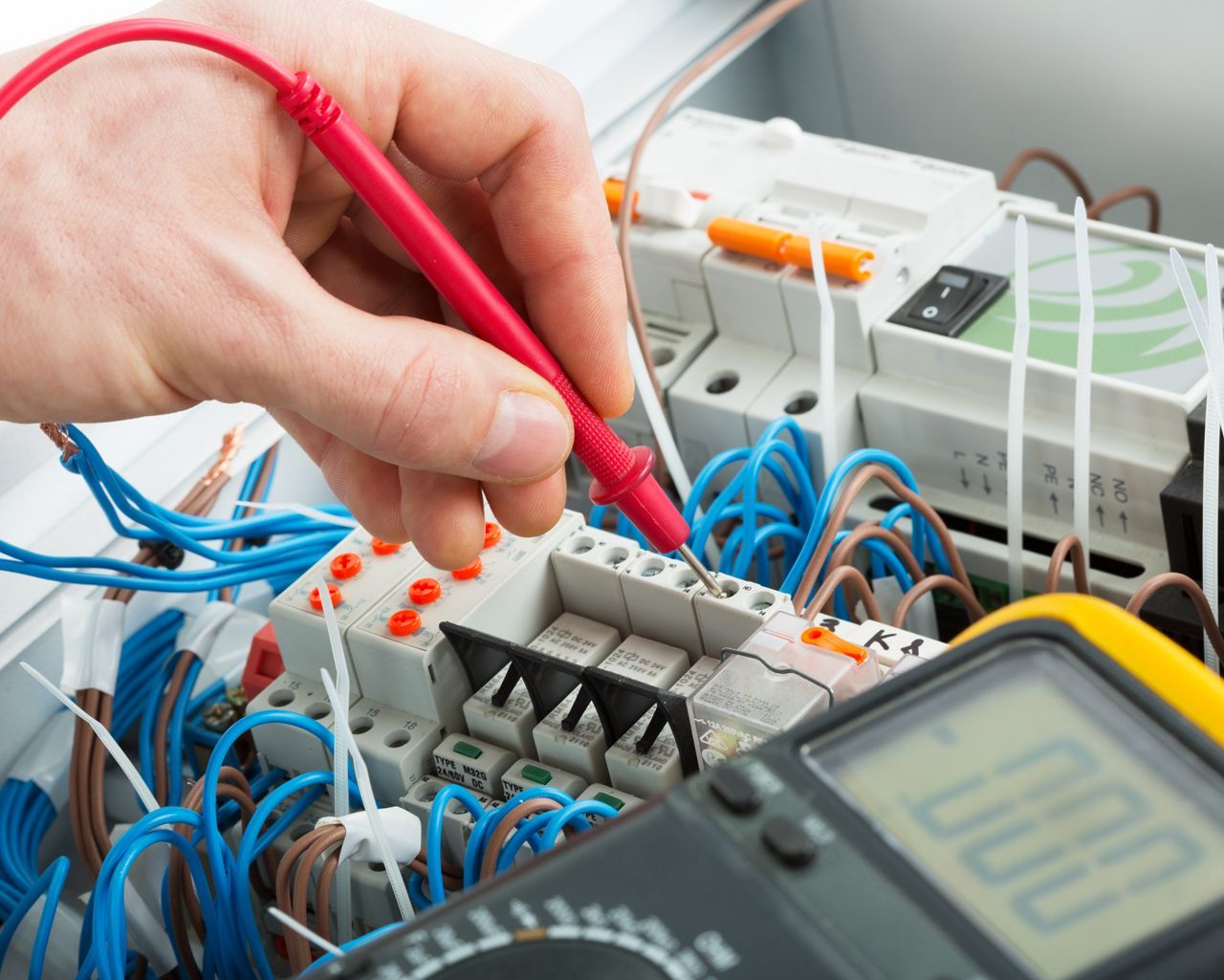 An electrician is using a multimeter to test a circuit board