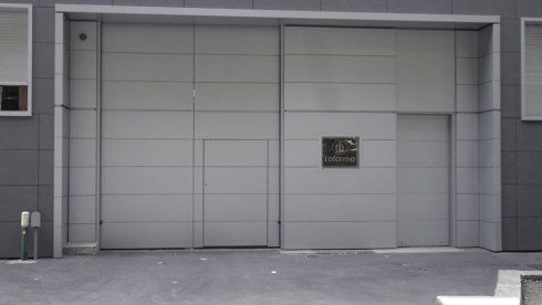 Una grande porta di garage grigia è aperta davanti a un edificio.