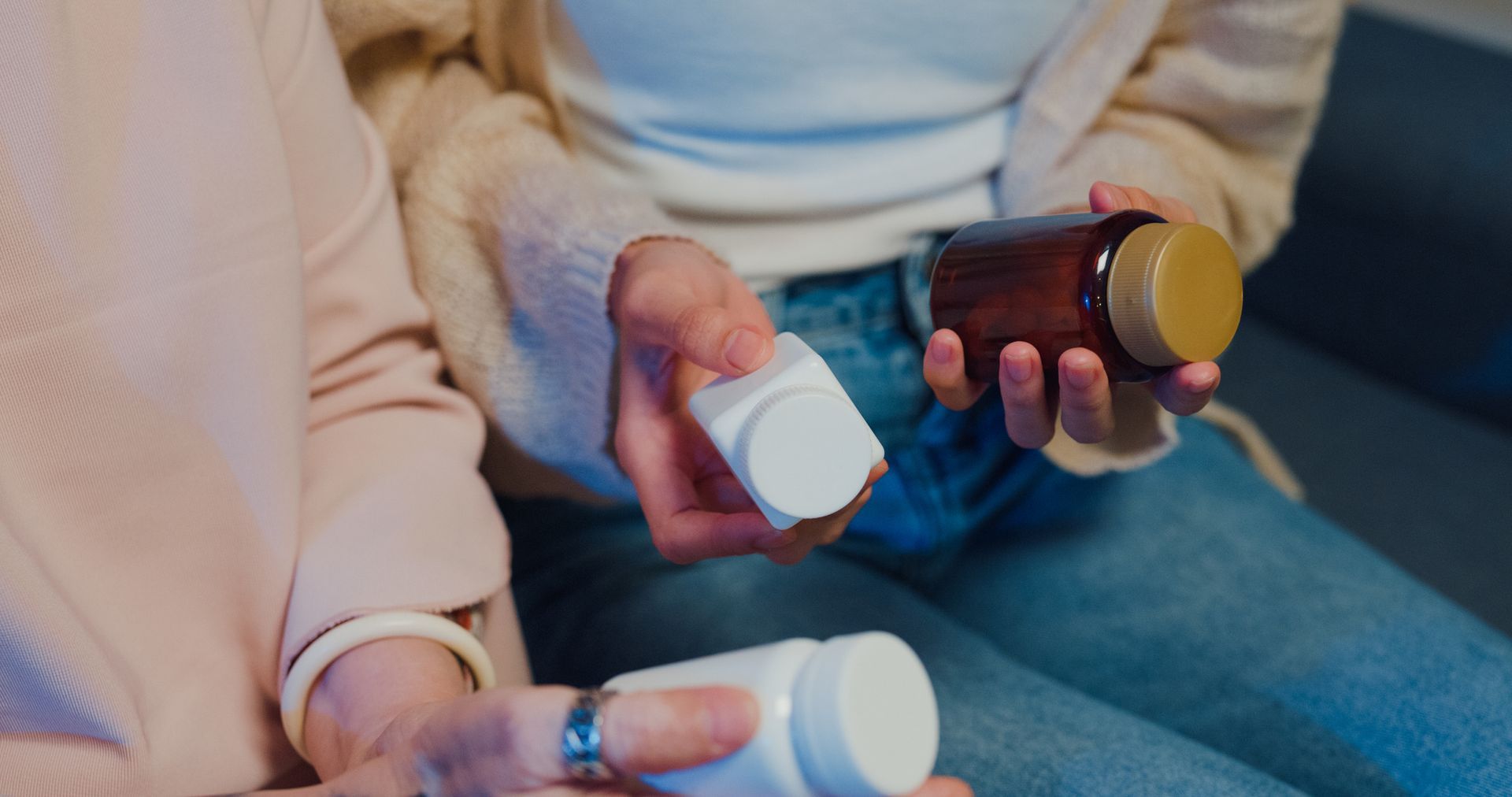 Two Person Are Sitting On A Couch Holding Bottles Of Pills — Chicago, IL — Chicagoland Home Physicians