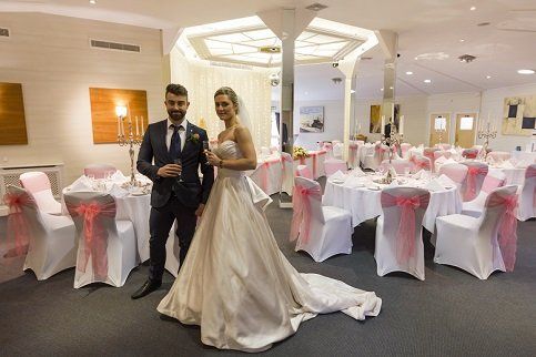 A bride and groom are posing for a picture in a room decorated for a wedding reception.