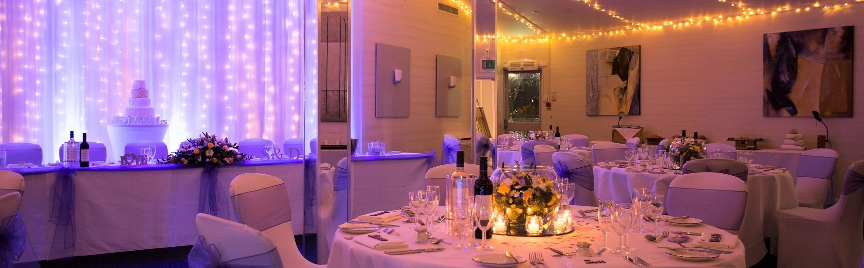 A room with tables and chairs set up for a wedding reception.