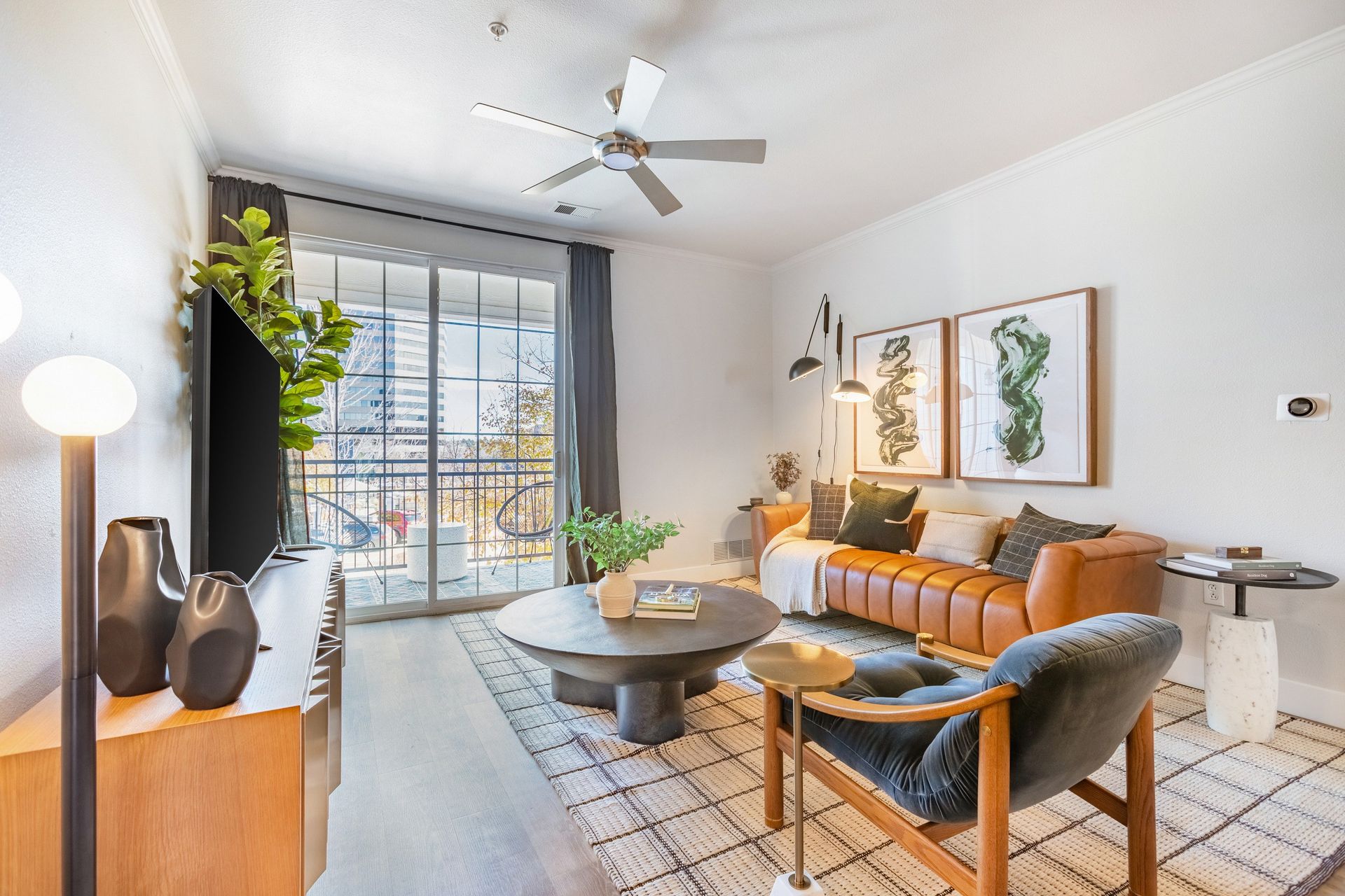 Modern living room with leather sofa, art, and balcony access.
