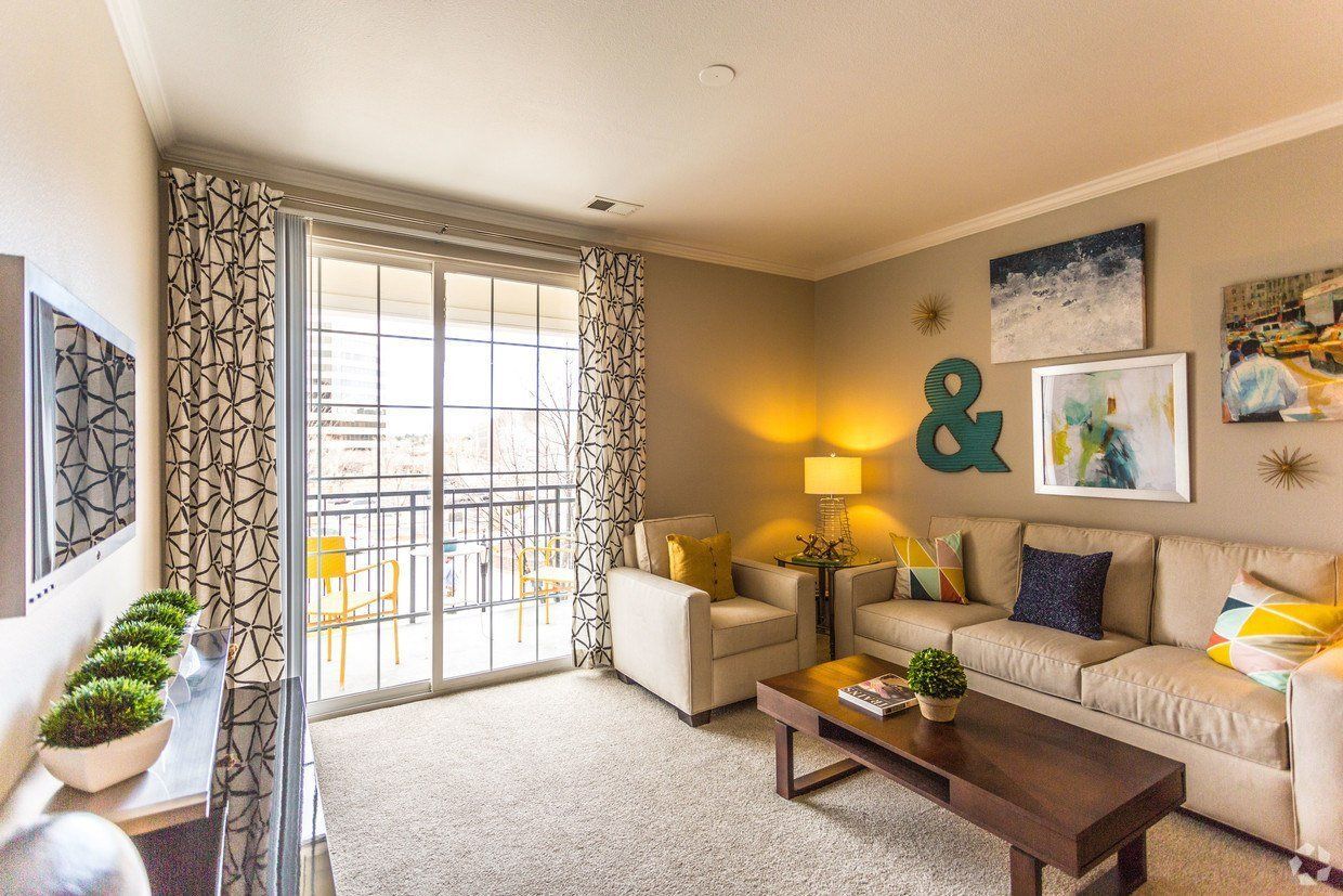 Living room with beige sofa, armchairs, and artwork; sliding glass door to balcony.