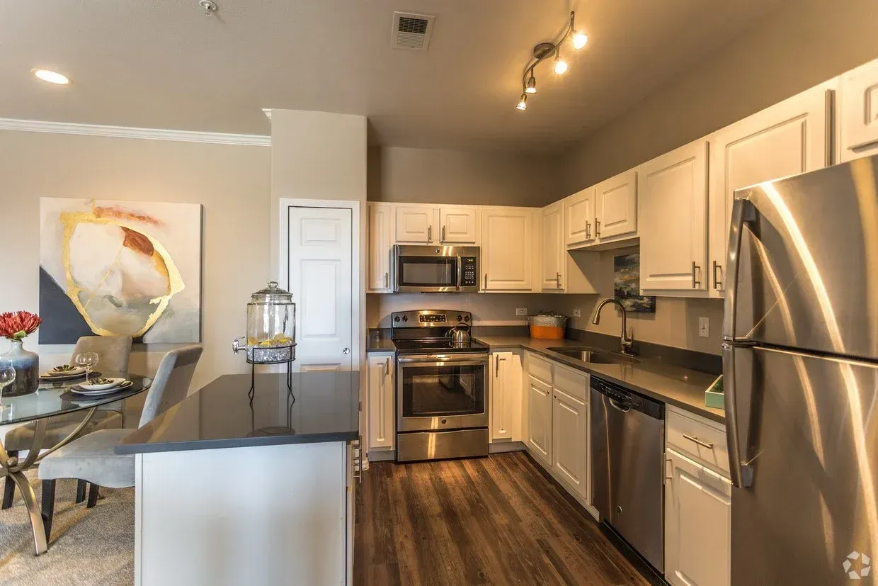 Modern kitchen with stainless steel appliances, white cabinets, dark countertops, and a breakfast bar.