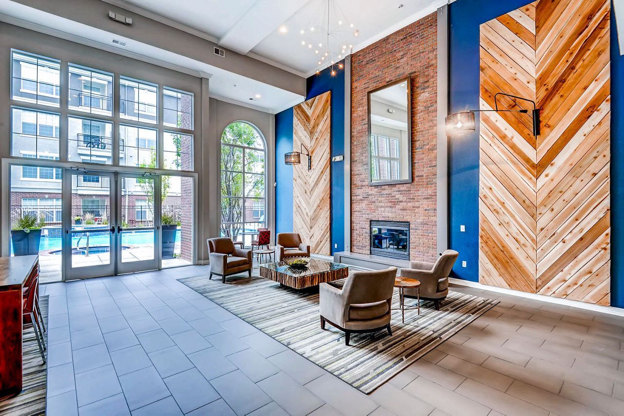 Lobby with seating, fireplace, large windows overlooking a pool. Blue walls with wood and brick accents.