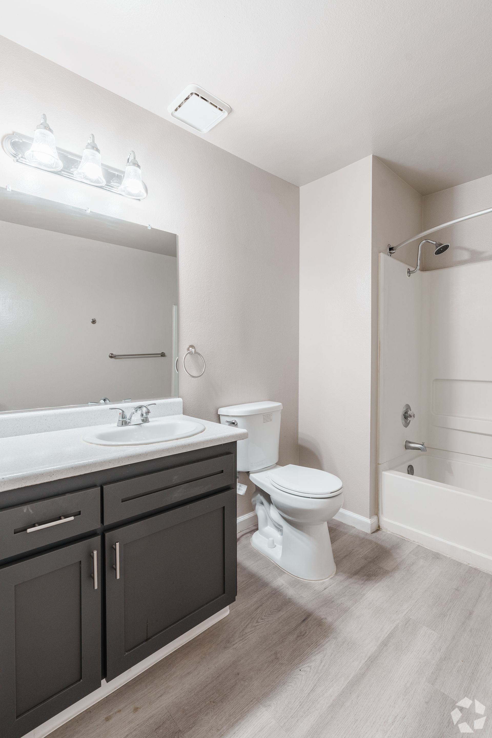 Bathroom with dark gray vanity, white toilet, and shower/tub. Gray walls and flooring.