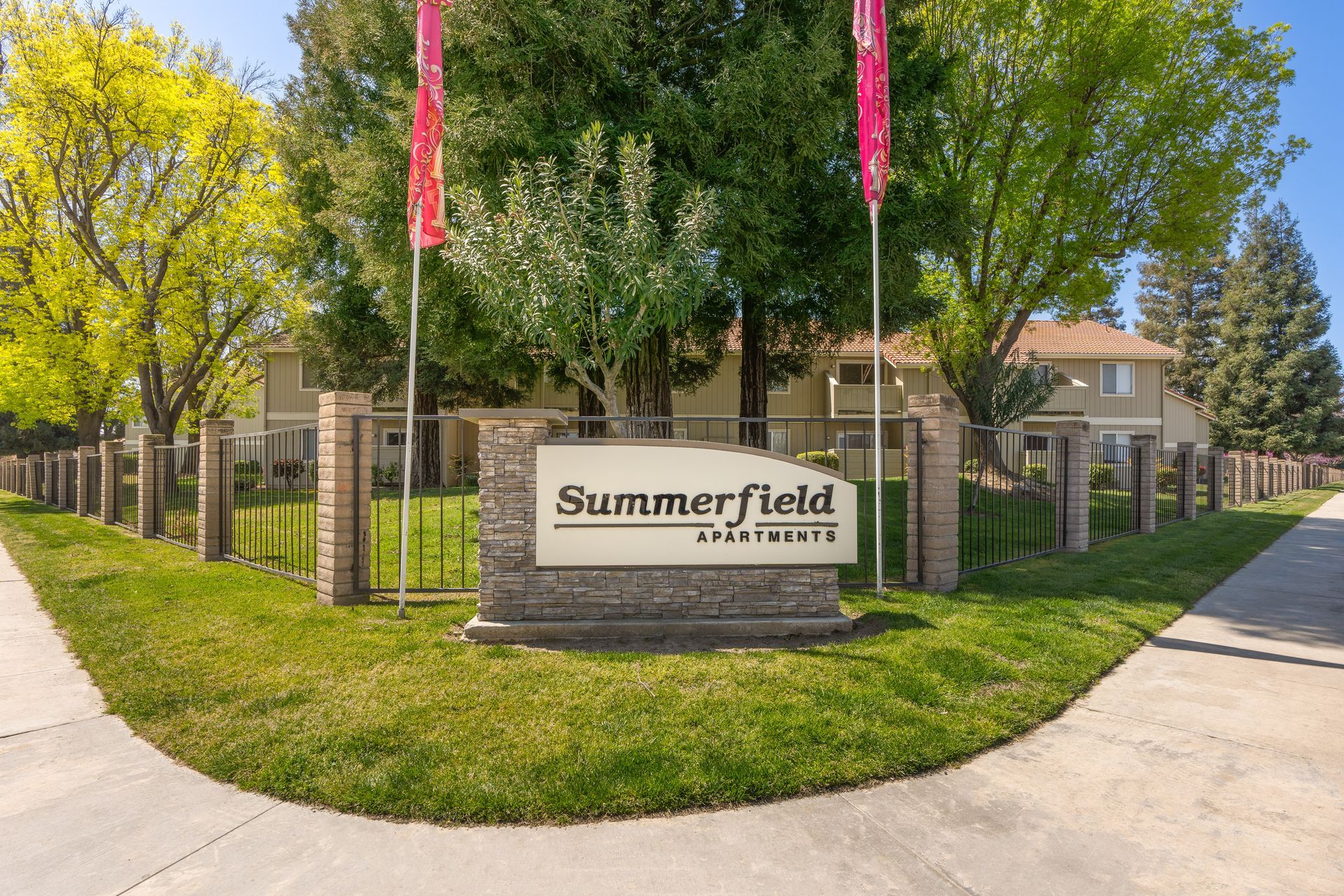 Summerfield Apartments entrance sign with a brick and stone base, surrounded by grass and trees.