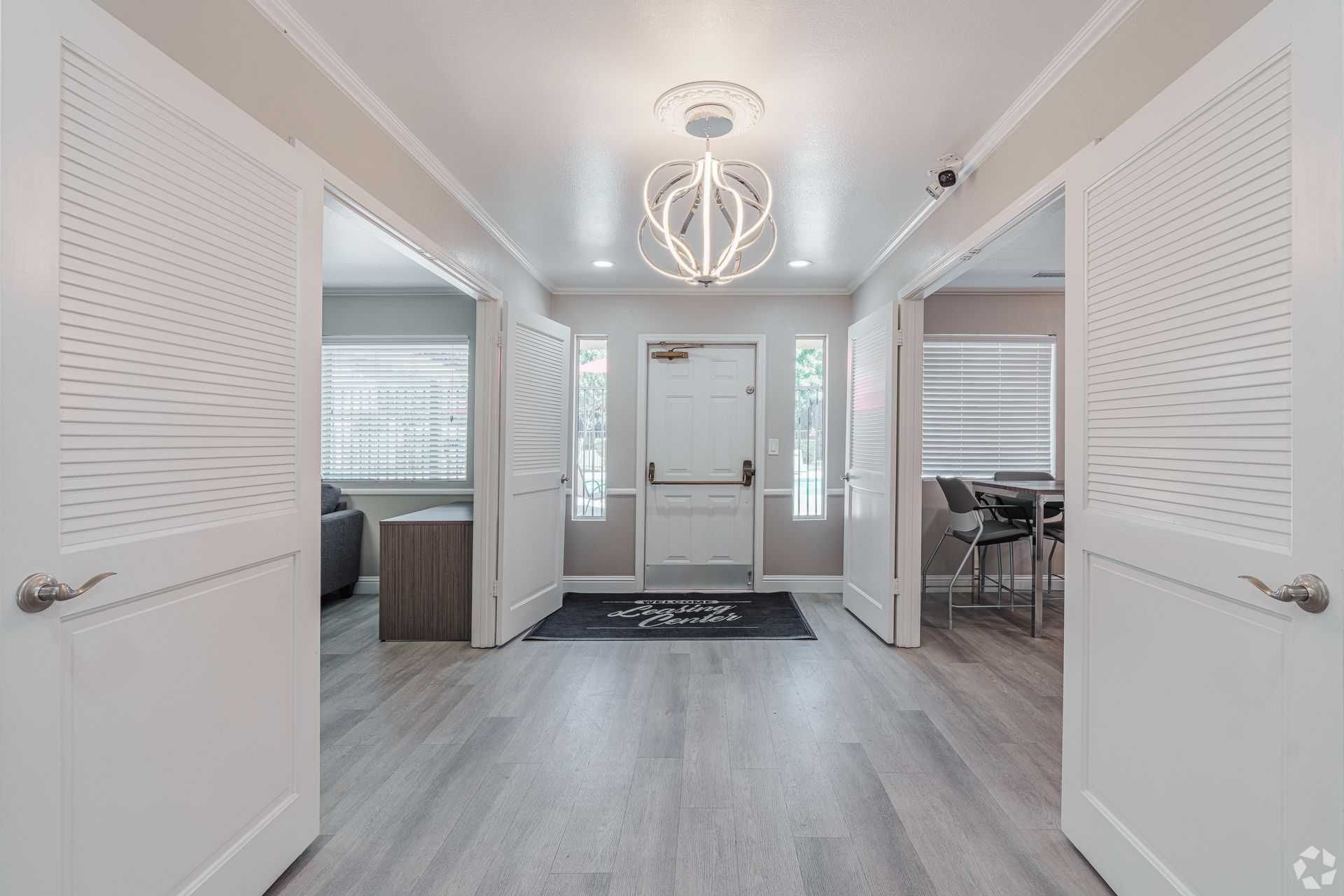 Hallway with white doors and grey wood-look flooring; a decorative light hangs from the ceiling.
