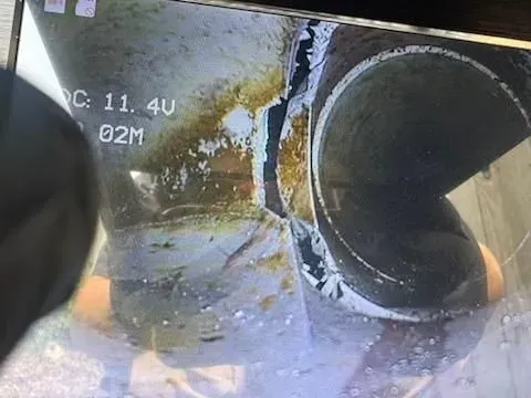 View of a damaged pipe, split open, showing the inside. Yellowish stains present.