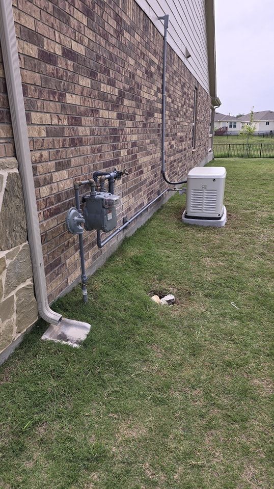 Brick building exterior with gas meter, generator, and downspout on grassy lawn.