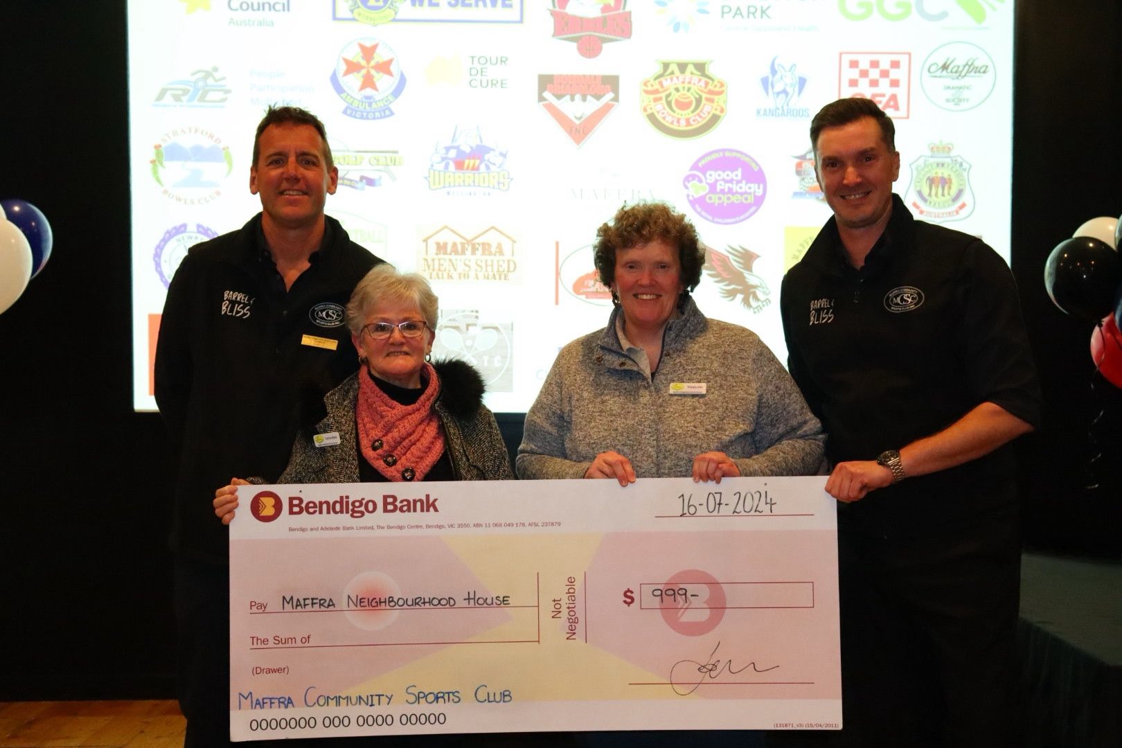 Four people holding a large check, with logos in background.