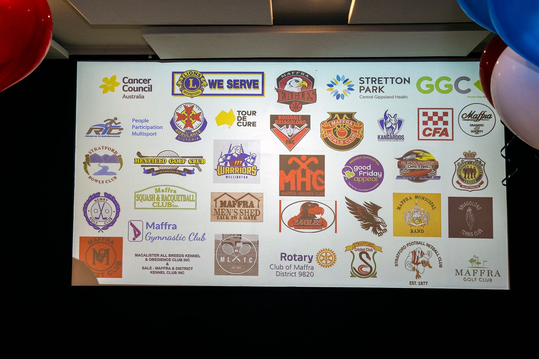 Sign with various logos of organizations, with balloons on either side.