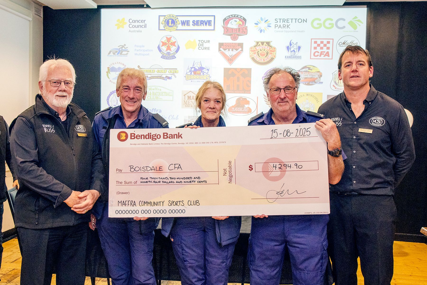 Five people holding a large check from Bendigo Bank, celebrating a donation.