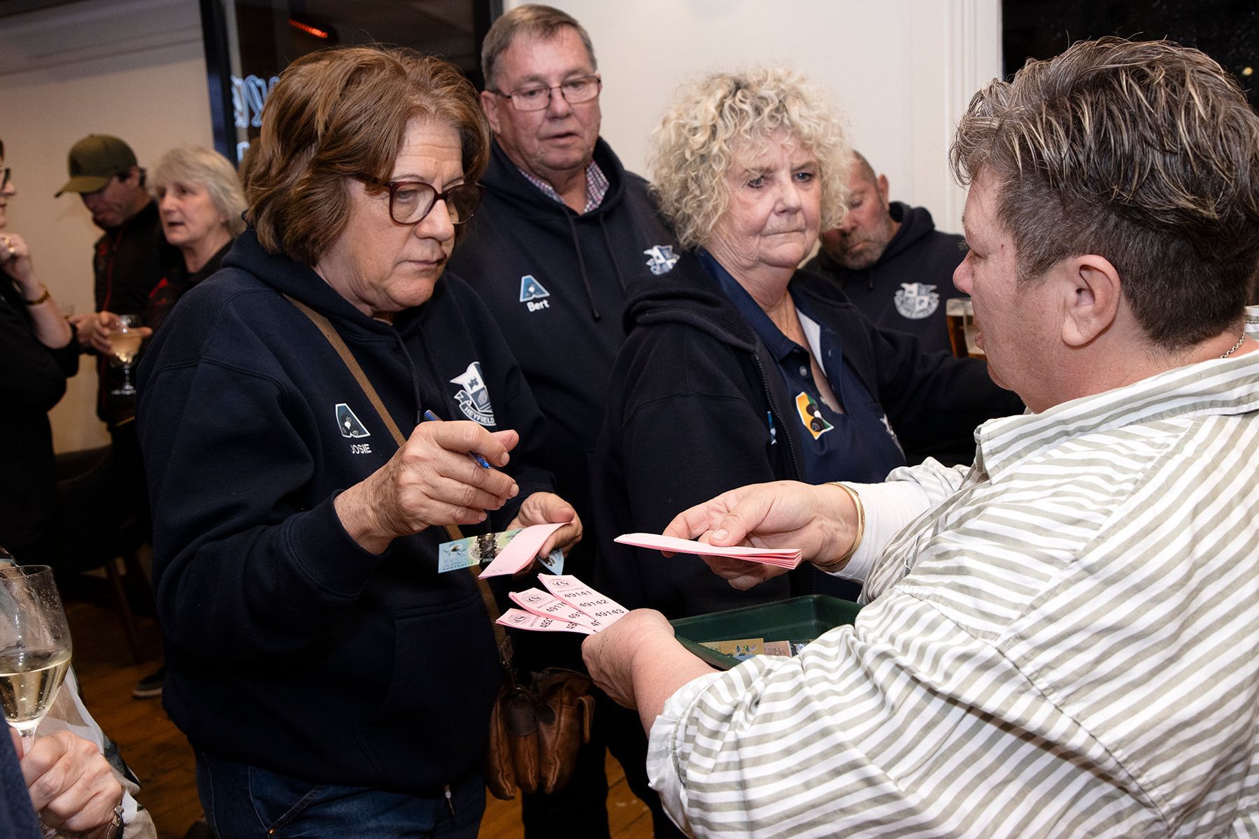 People interacting; a person dealing cards to a group. Indoors, casual setting.