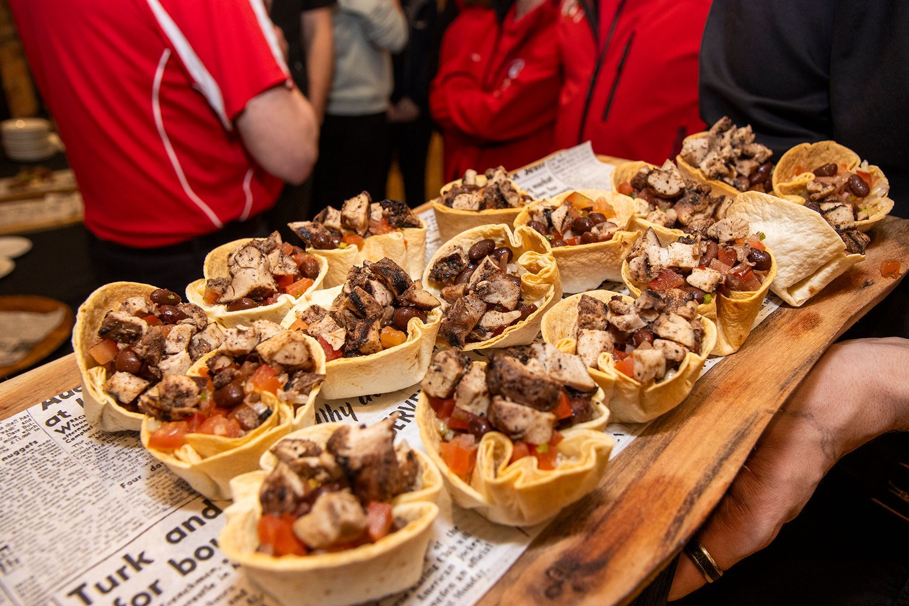 A tray of appetizers: mini taco shells filled with diced meat and tomatoes.