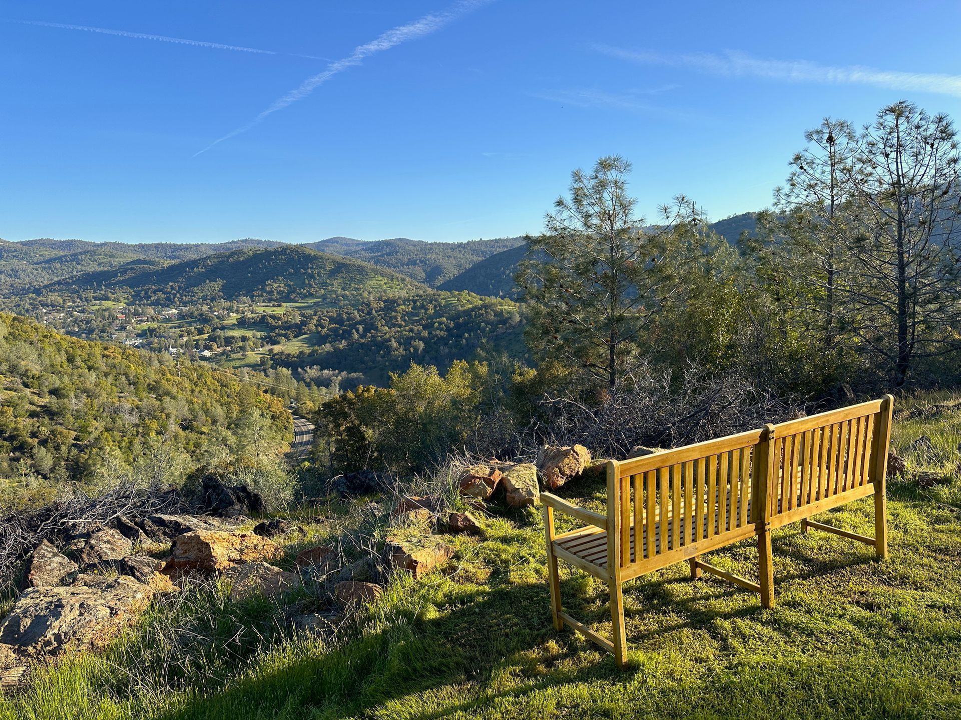 Two wooden benches are sitting on top of a grassy hill overlooking a valley.