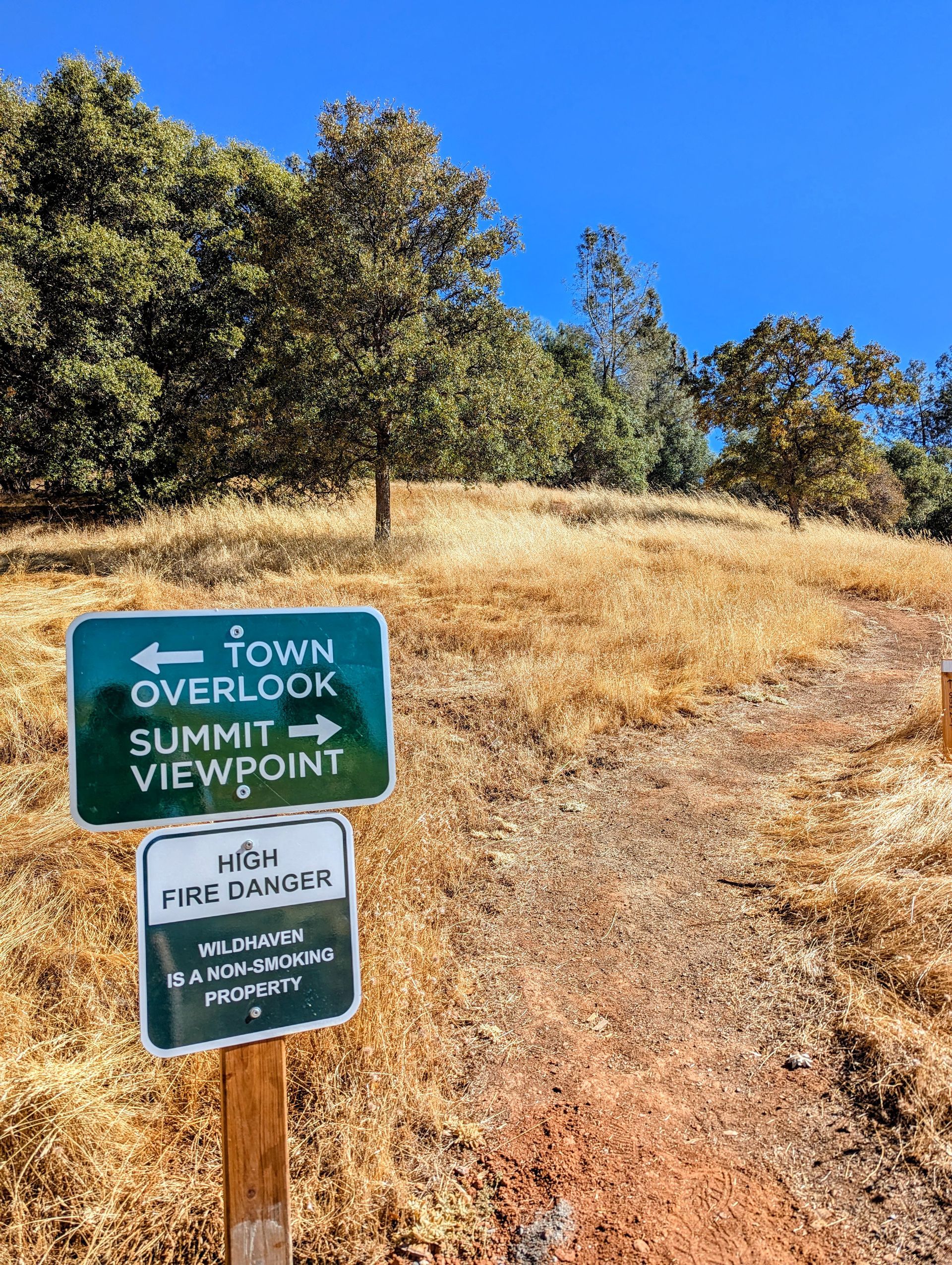 A sign on a wooden post shows the way to town overlook and summit viewpoint.