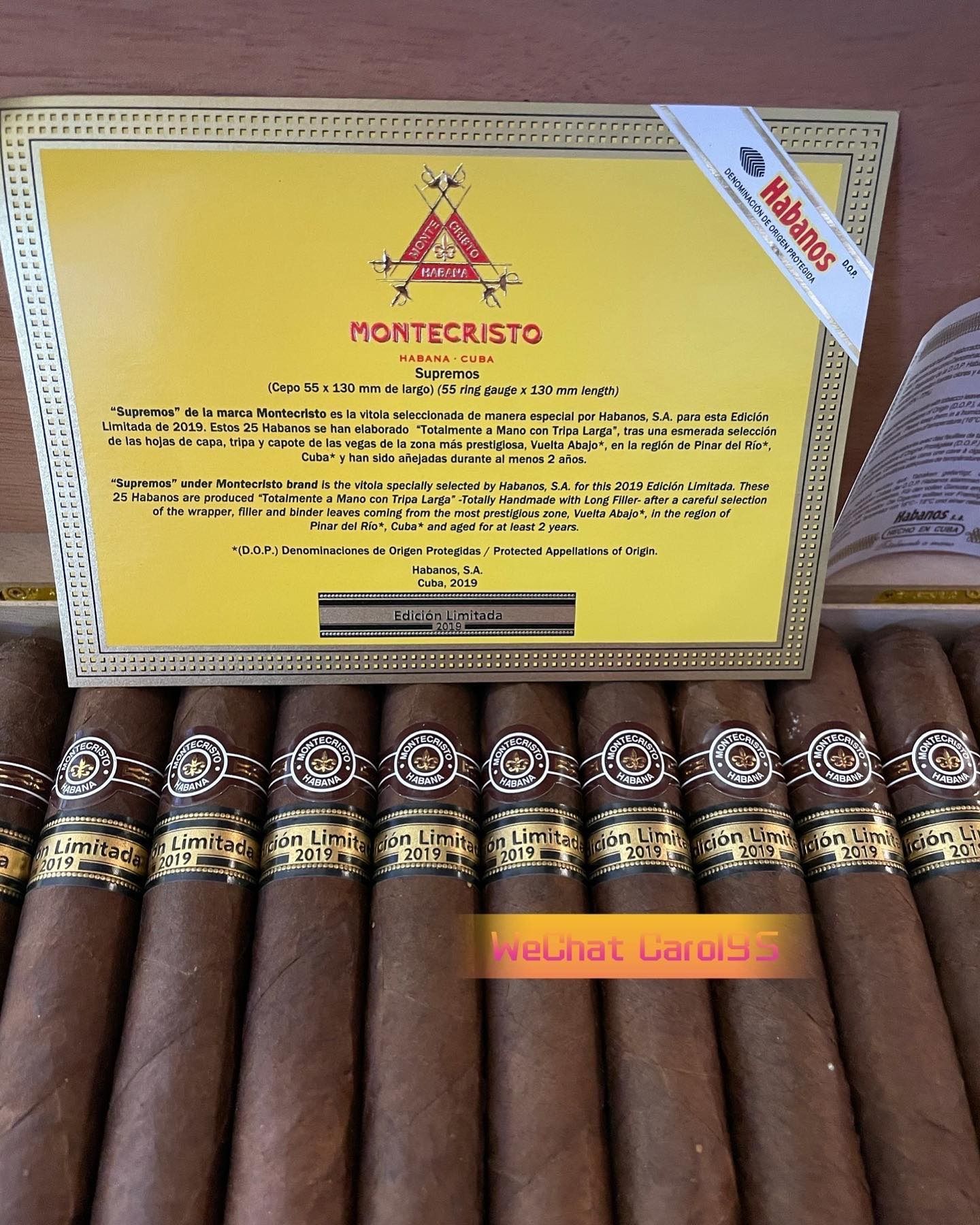 Scatola aperta di sigari Montecristo, primo piano. I sigari sono marroni, le fascette sono dorate. La scatola è gialla.