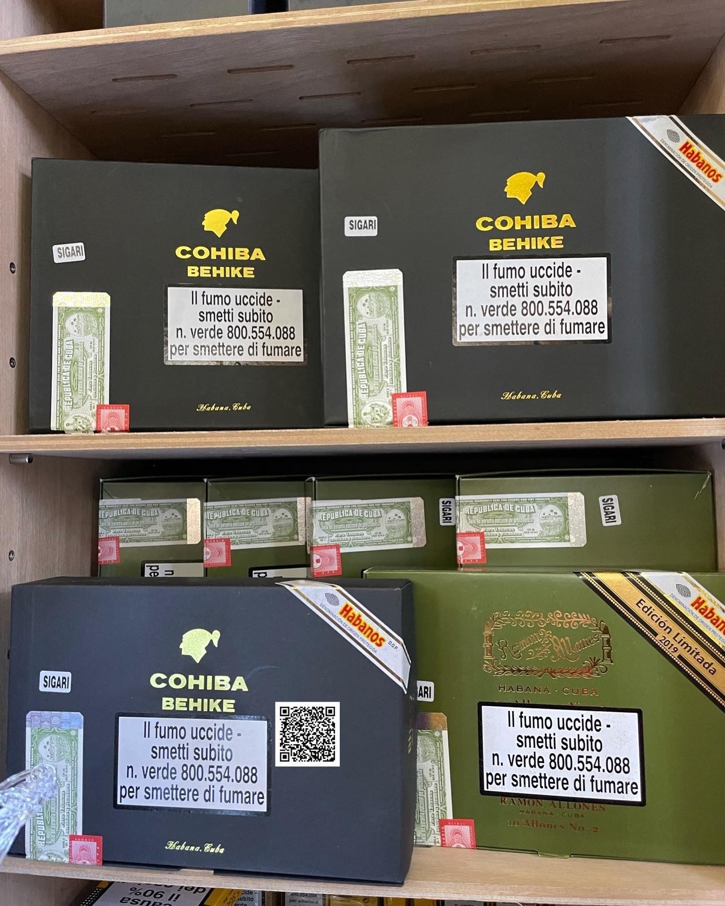 Scaffali pieni di scatole di sigari Cohiba, per lo più verde scuro e nere, con etichette bianche e rosse.