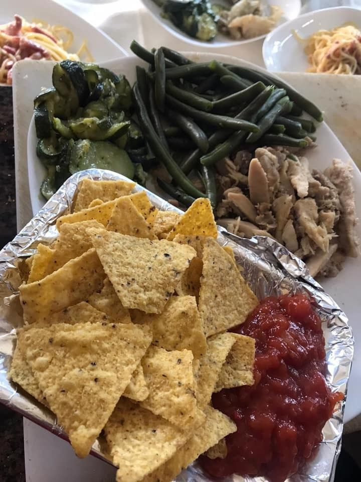 Piatto di cibo: tortilla chips e salsa, fagiolini, pollo e altre verdure.