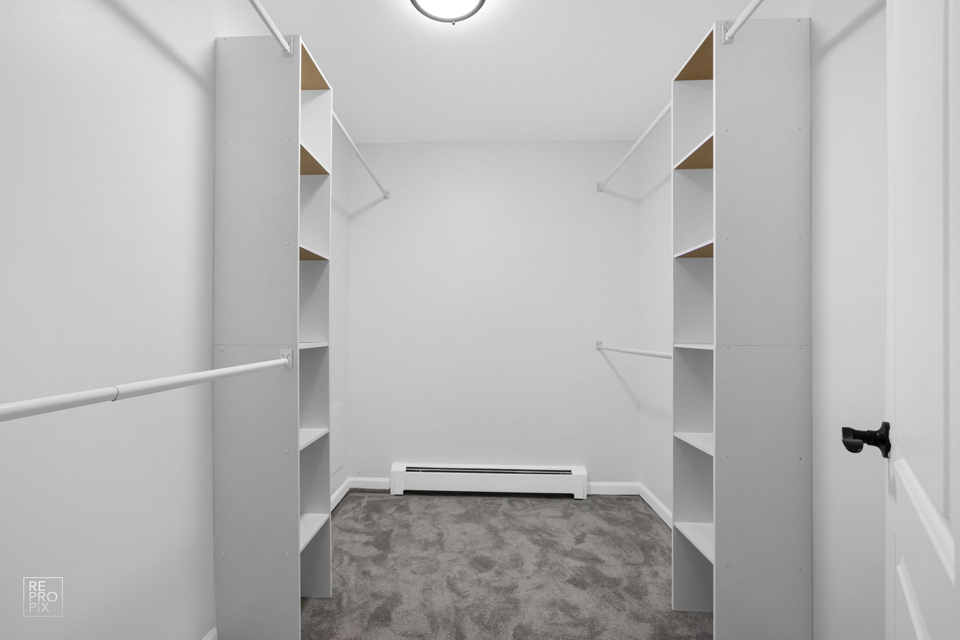 An empty walk in closet with shelves and a radiator.