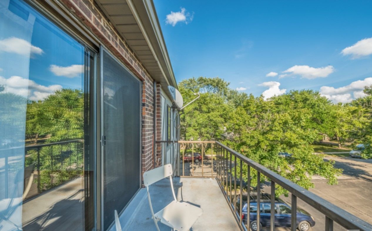 A balcony with a chair and a sliding glass door.