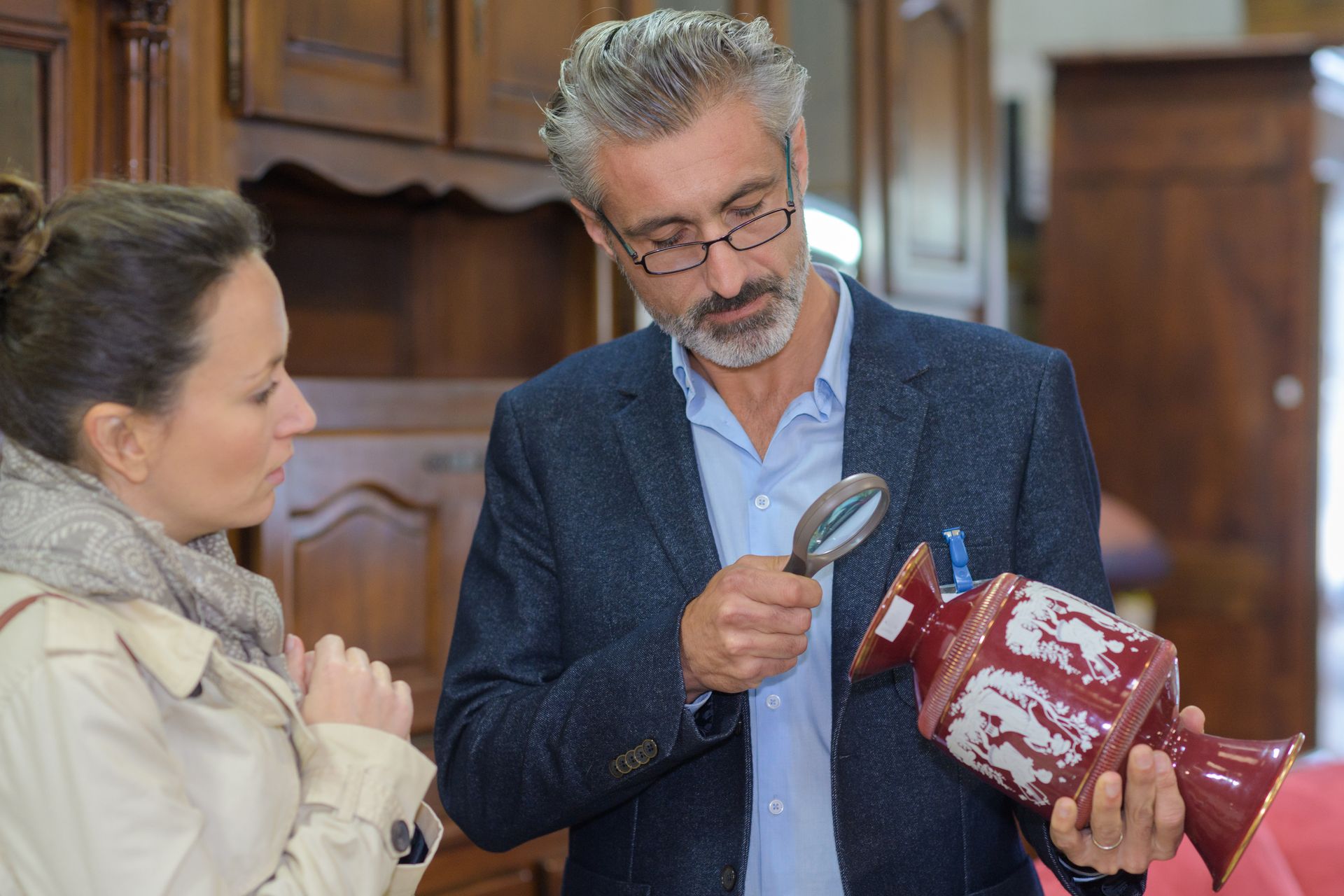 Antique dealer valuing a vase while a woman next to him waits for a response.