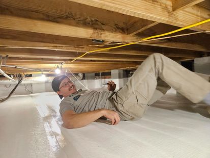 A man is laying on the floor of a basement.
