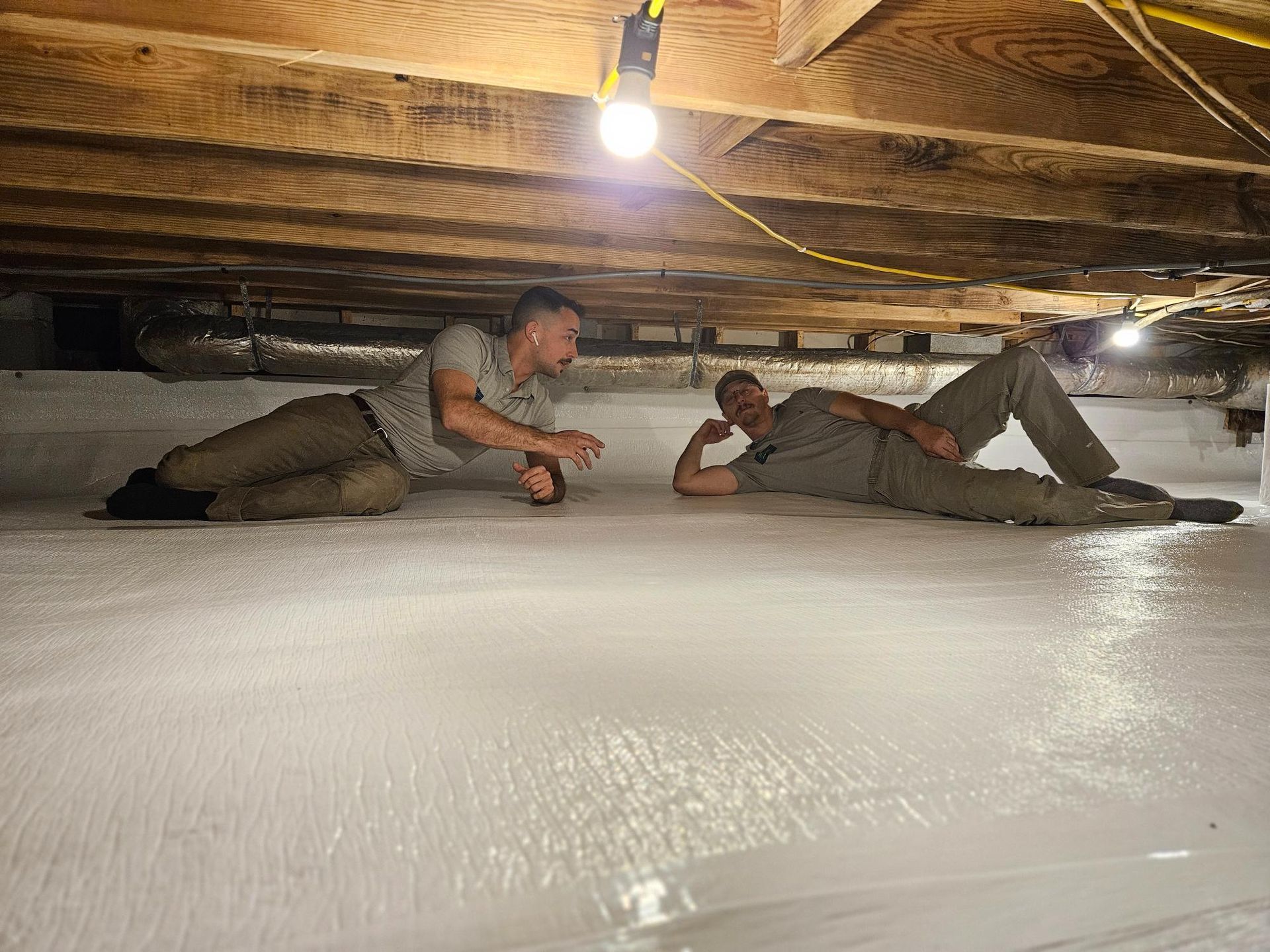 Two men are laying on the floor of a basement.
