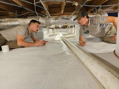 Two men are laying on the floor of a basement.
